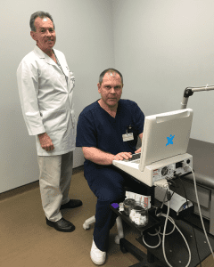 Two orthopedic specialists standing in front of a computer screen in a sports clinic.