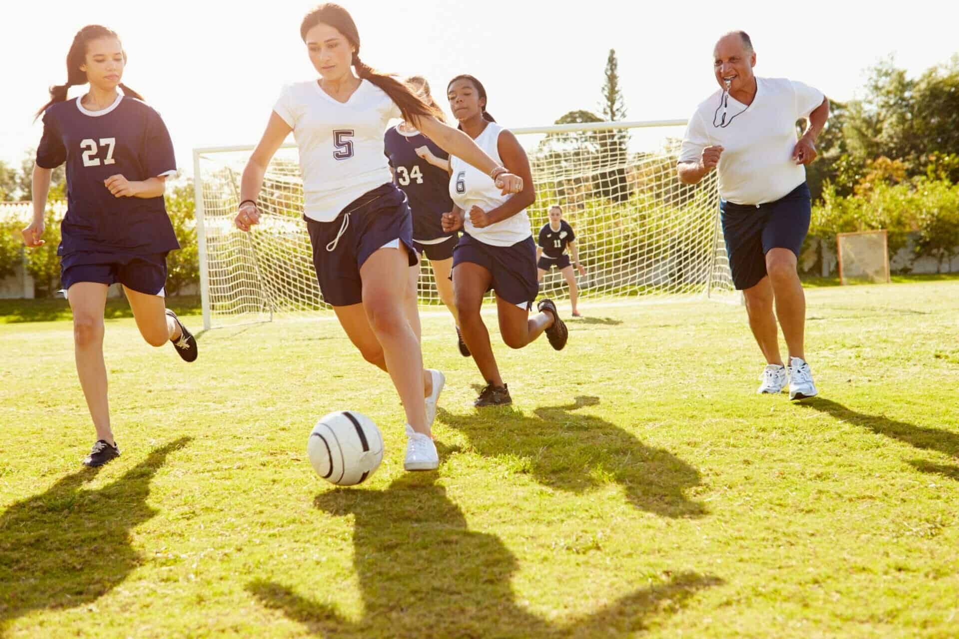 A group of young athletes participating in a sport clinic on a soccer field.