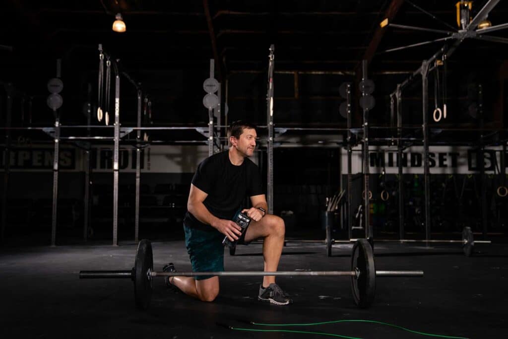 A man exercising with a barbell in a sport clinic gym.