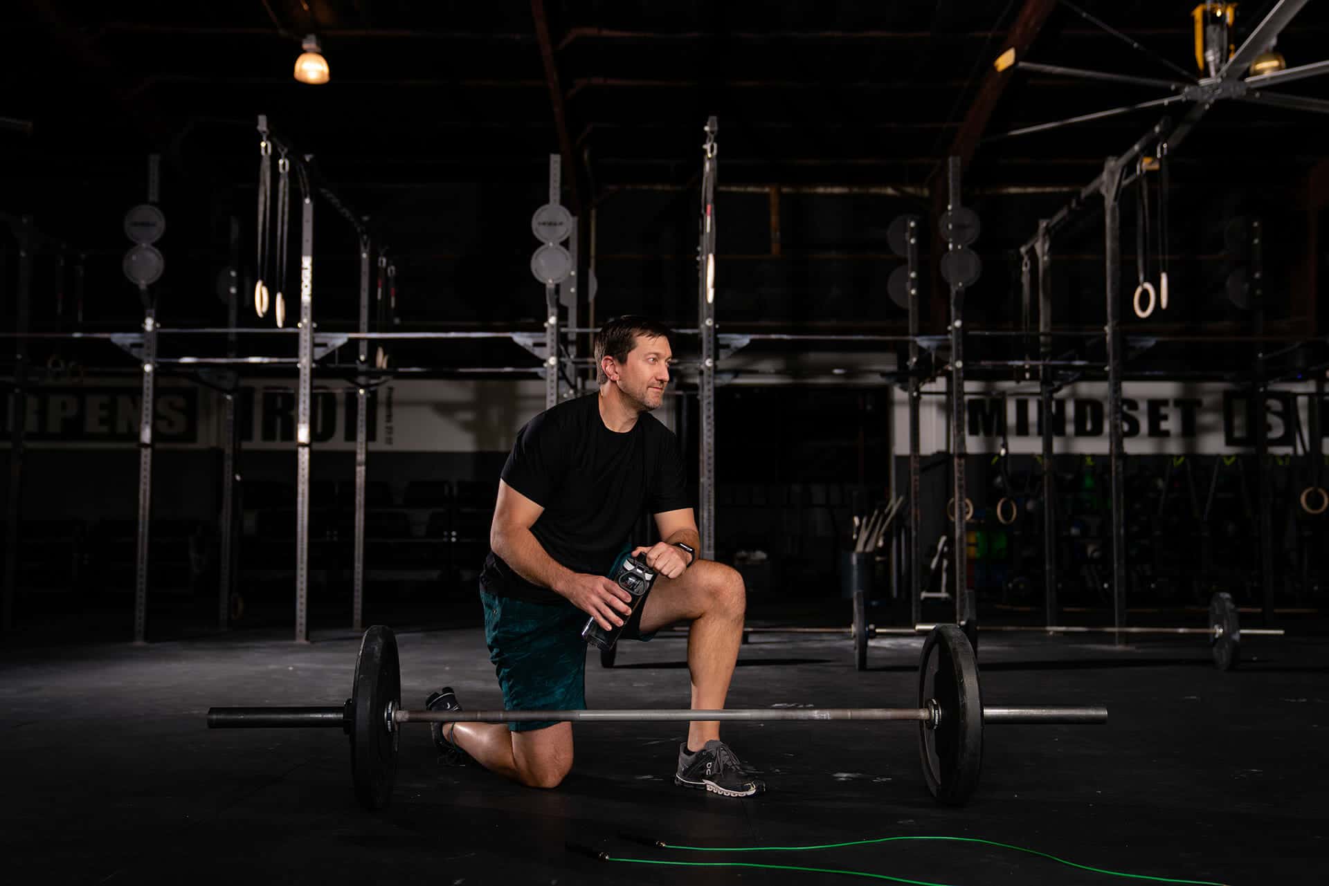 A man exercising with a barbell in a sport clinic gym.