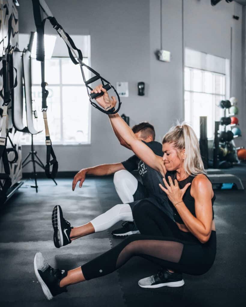 Two individuals utilizing TRX exercises in an orthopedic sport clinic.